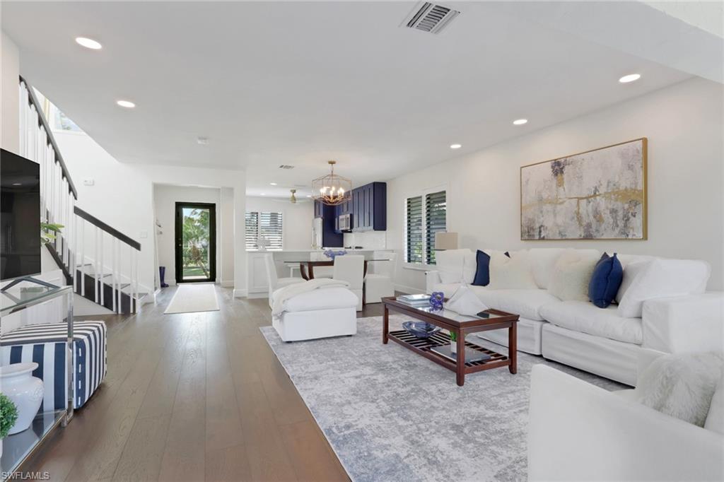 Living room with a chandelier, wood-type flooring, recessed lighting, and stairs