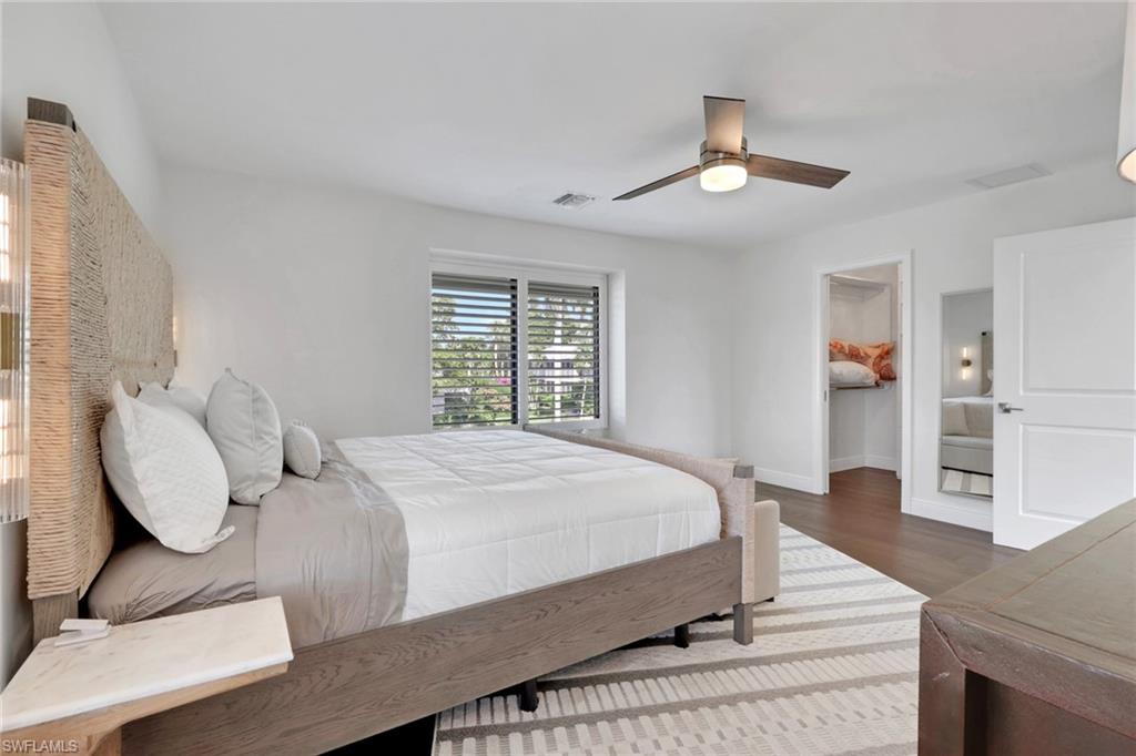 Bedroom featuring a walk in closet, ceiling fan, and dark wood-style floors