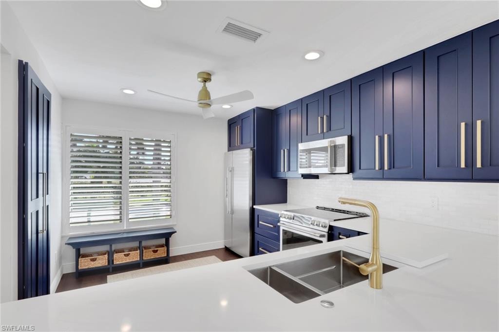 Kitchen with blue cabinets, appliances with stainless steel finishes, recessed lighting, a ceiling fan, and backsplash