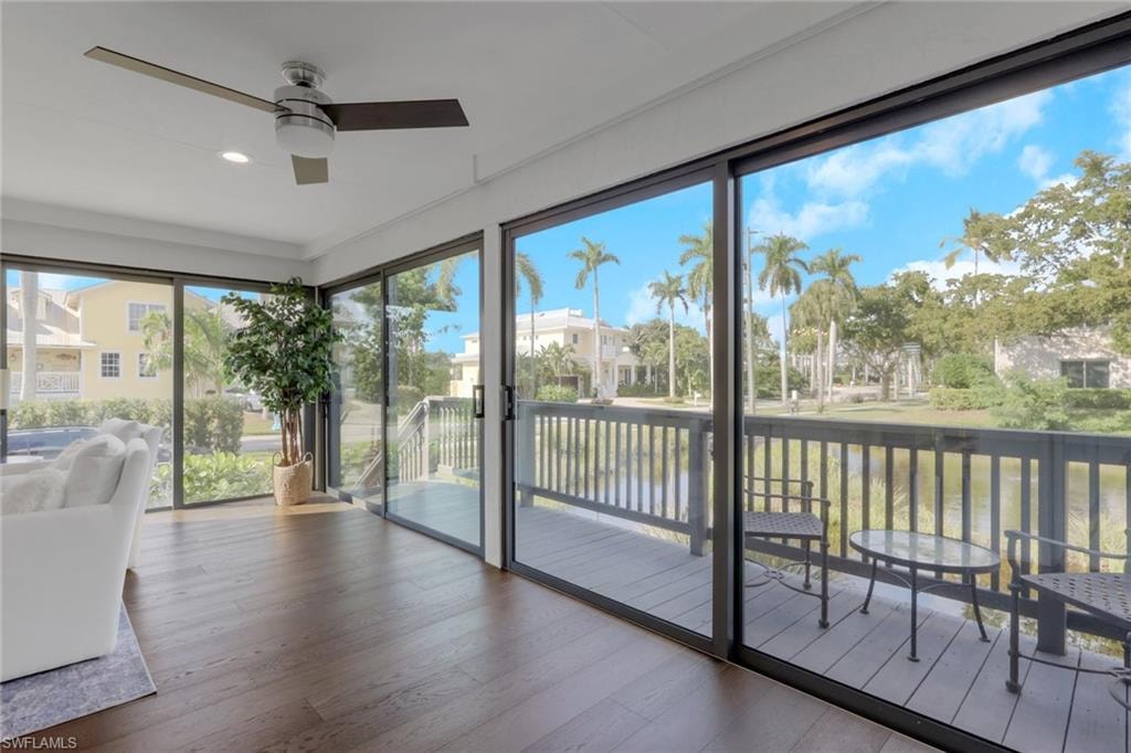 Sunroom / solarium with hardwood / wood-style flooring, a water view, and recessed lighting