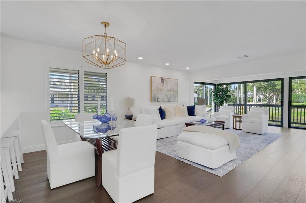 Dining space with dark wood-type flooring, healthy amount of natural light, recessed lighting, and a chandelier