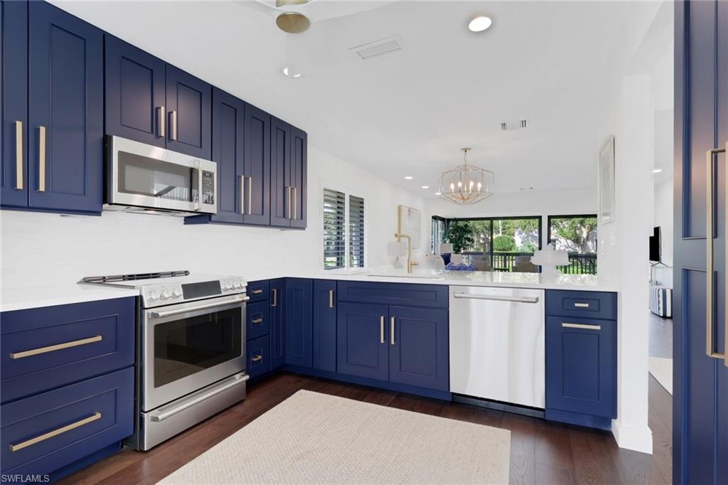 Kitchen with blue cabinetry, stainless steel appliances, a chandelier, and recessed lighting