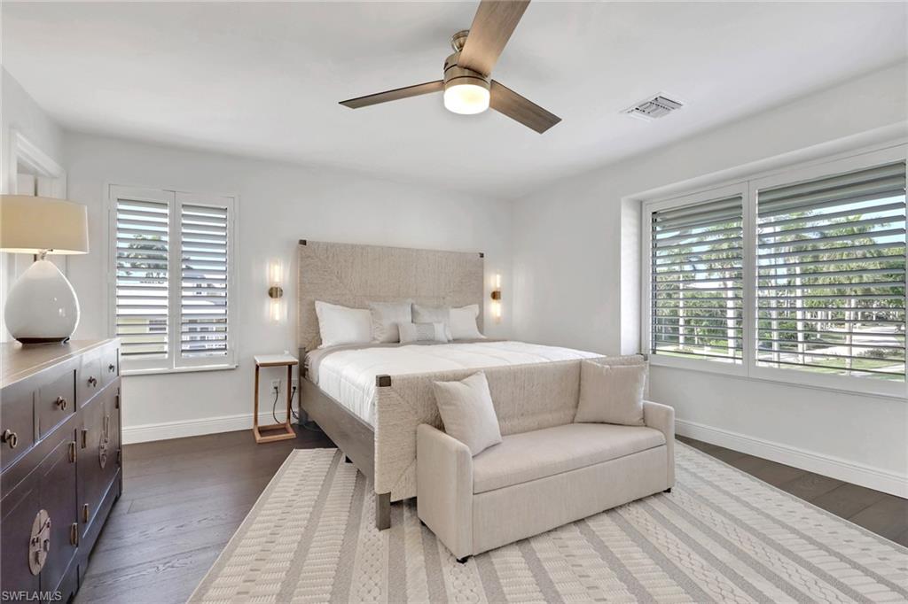 Bedroom featuring a ceiling fan, multiple windows, and dark wood finished floors