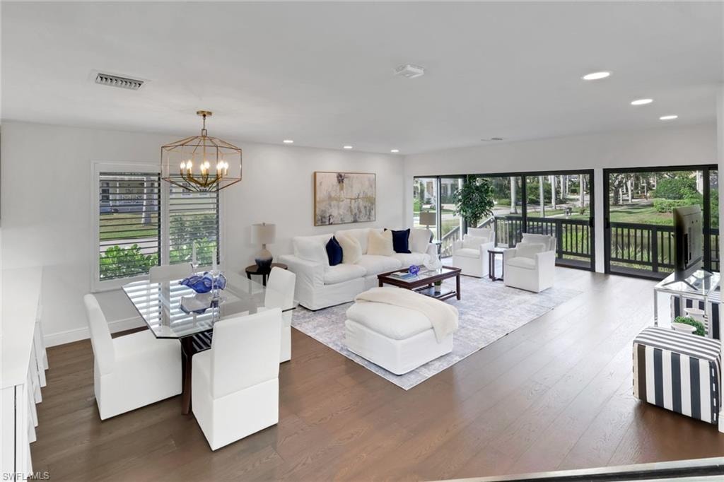 Living area with dark wood finished floors, a chandelier, and recessed lighting