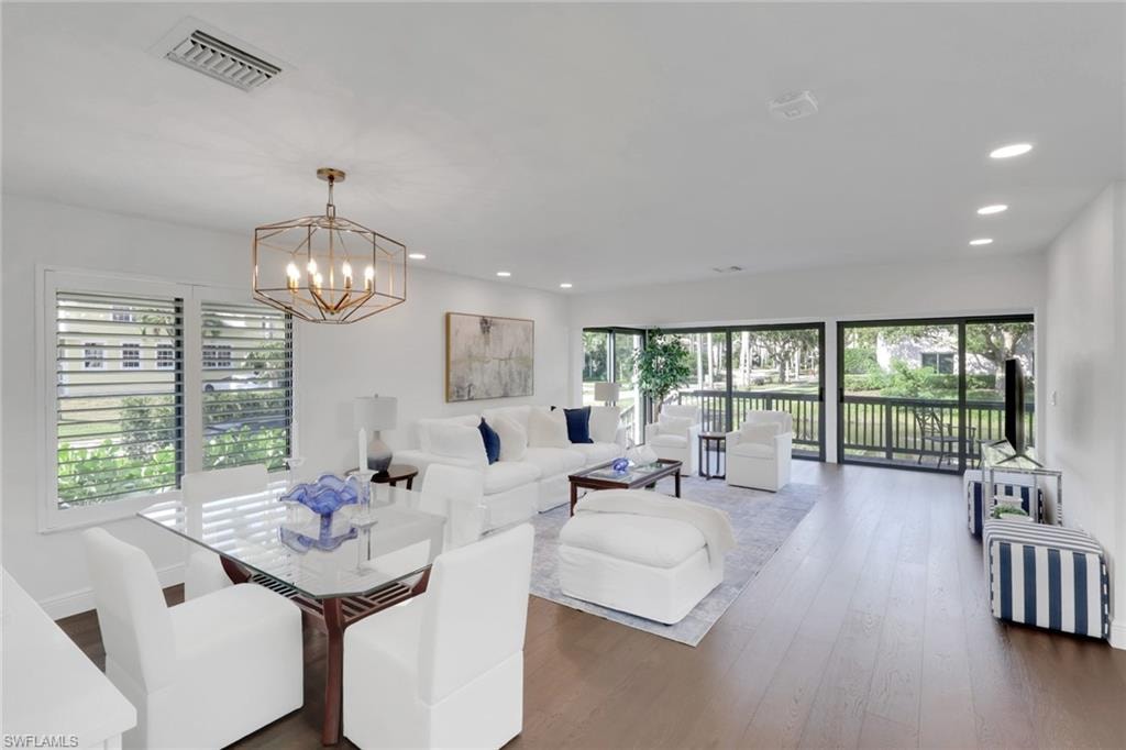 Dining space featuring dark wood finished floors, healthy amount of natural light, recessed lighting, and a chandelier