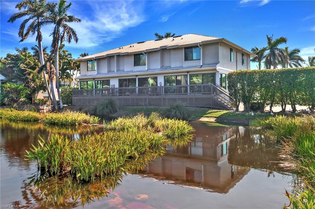 Back of house with a metal roof, stairs, a deck with water view, and stucco siding