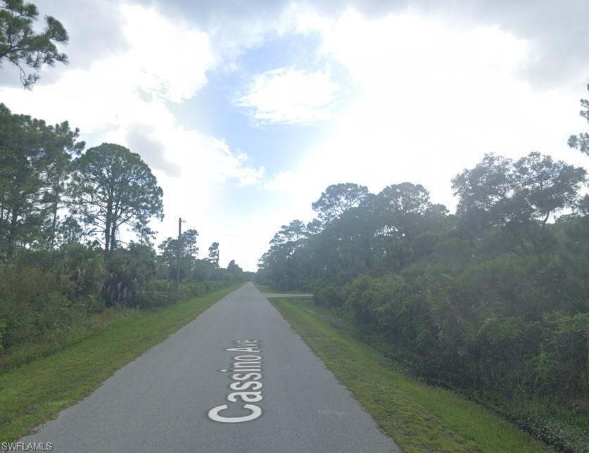 View of asphalt road featuring view of wooded area