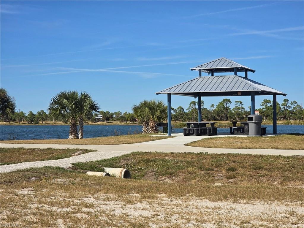 Surrounding community with a gazebo, a water view, a patio, and a lawn