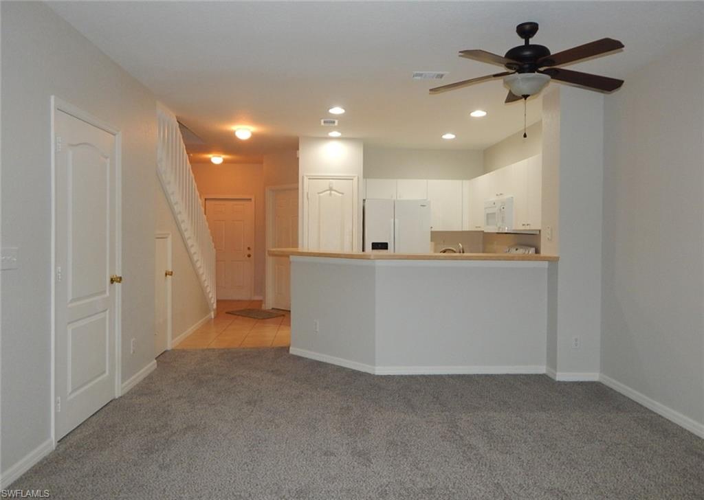 Kitchen featuring white appliances, ceiling fan, light carpet, white cabinets, and dining area