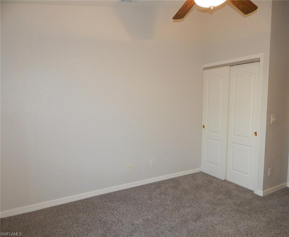 Carpeted guest bedroom with baseboards and a ceiling fan