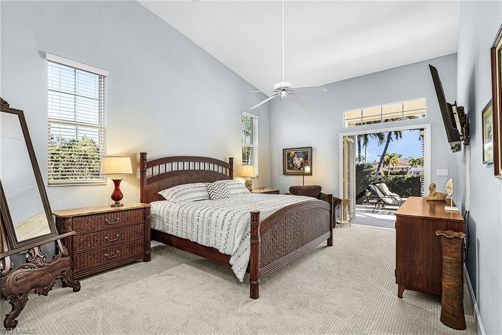 Bedroom with access to exterior, light carpet, a towering ceiling, and ceiling fan