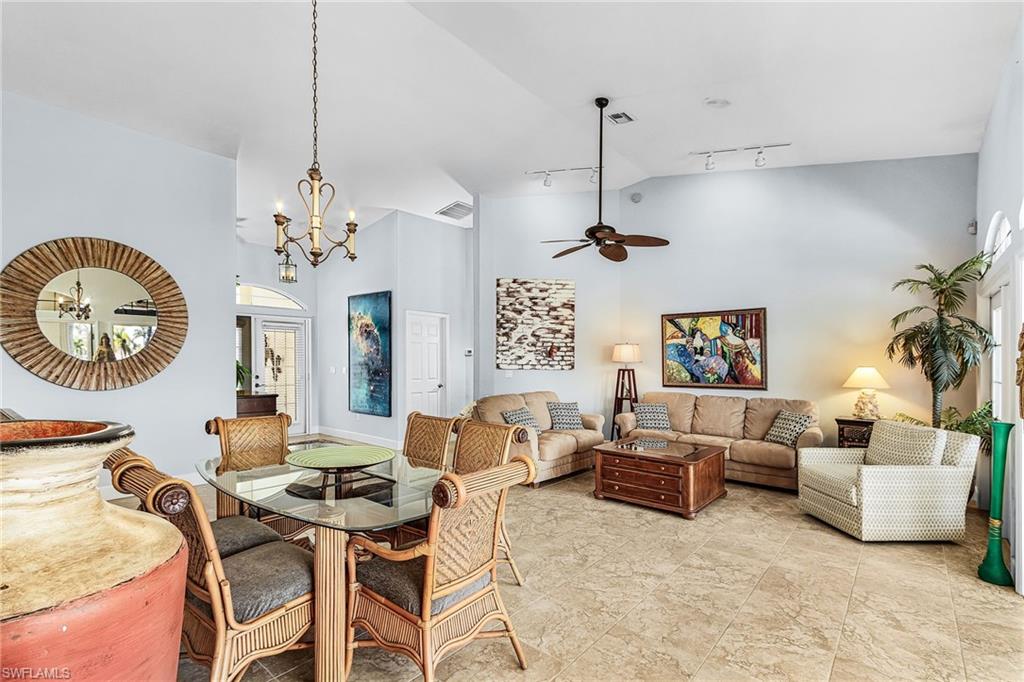 Dining room with high vaulted ceiling, a chandelier, track lighting, and a ceiling fan