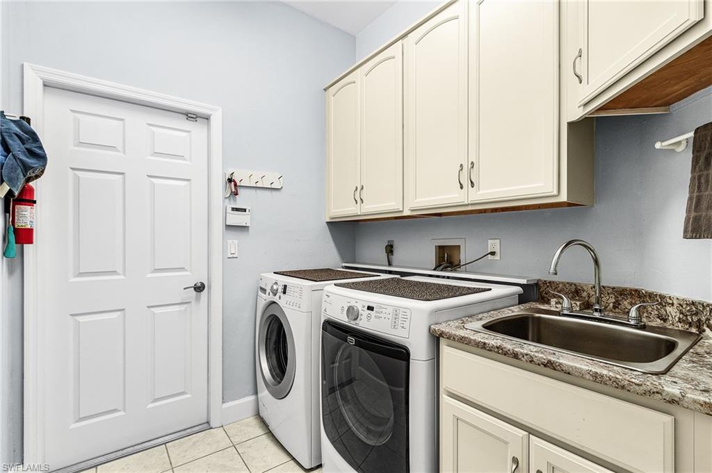 Laundry room with light tile patterned floors, washer and dryer, and cabinet space