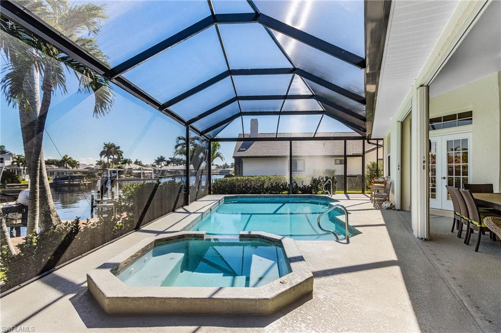View of pool featuring french doors, a patio, a sunroom, a water view, and glass enclosure