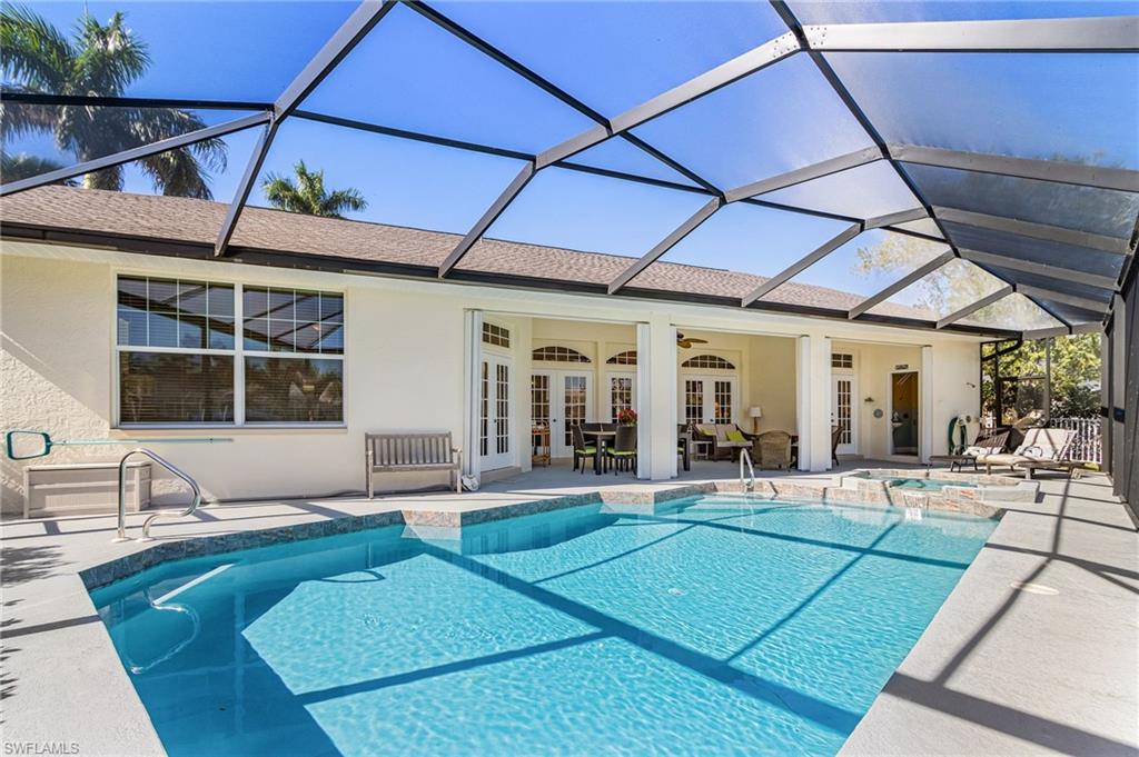 View of pool featuring a patio, a sunroom, glass enclosure, a pool with connected hot tub, and french doors