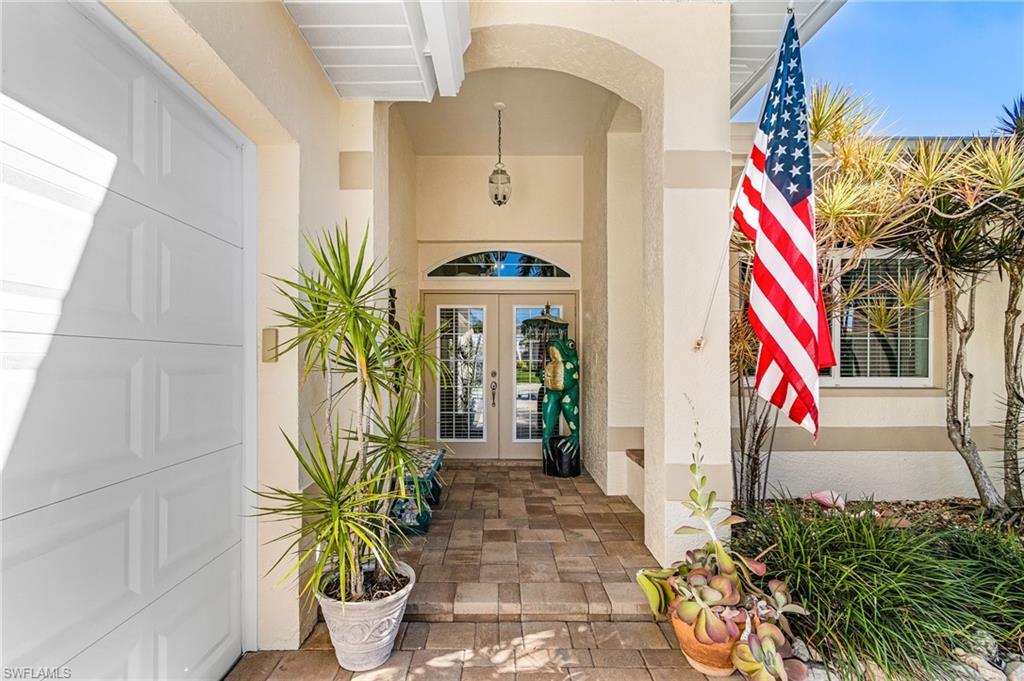 Doorway to property featuring french doors, stucco siding, and covered porch