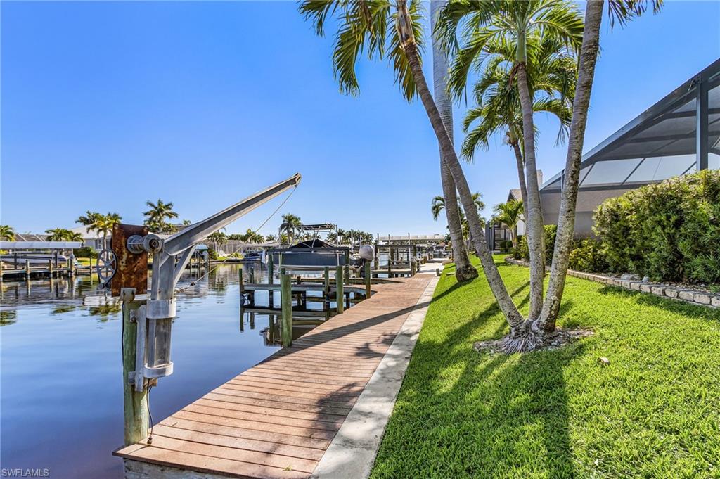 Dock area featuring boat lift, a water view, and a lawn