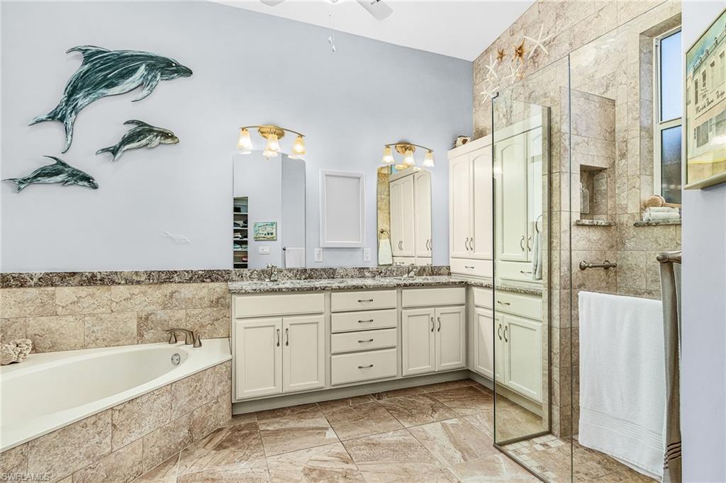 Bathroom featuring double vanity, a bath, a ceiling fan, and a stall shower