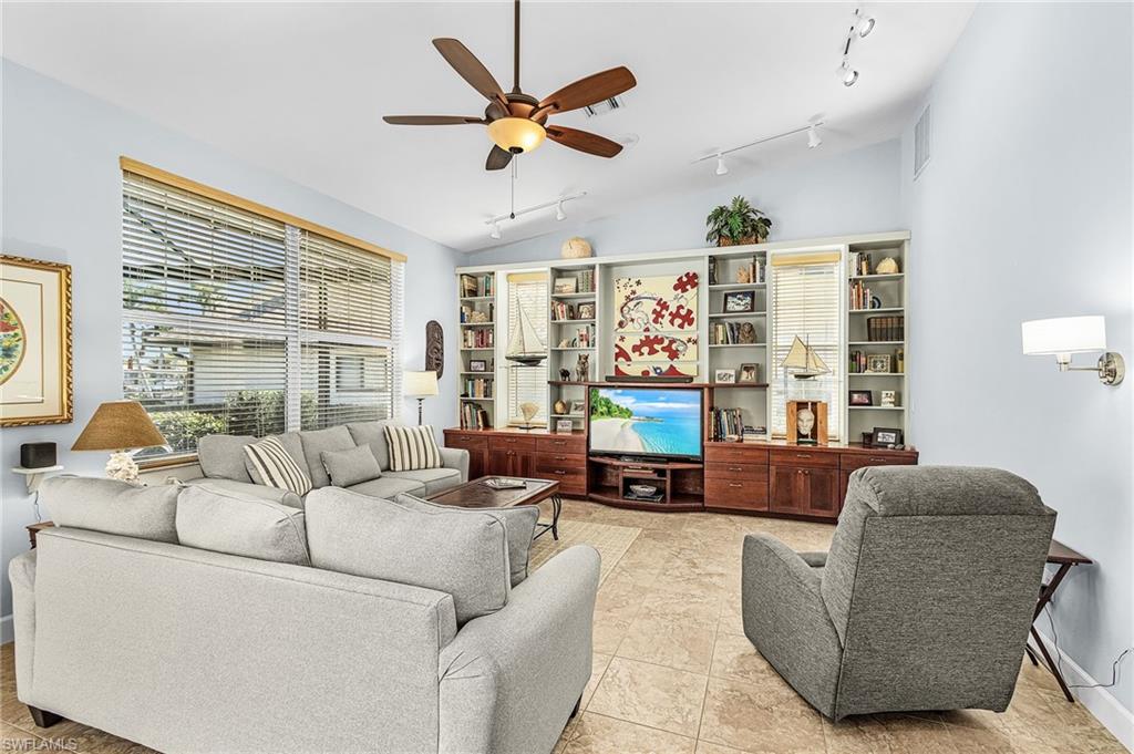 Living room featuring a ceiling fan, vaulted ceiling, track lighting, and light tile patterned floors