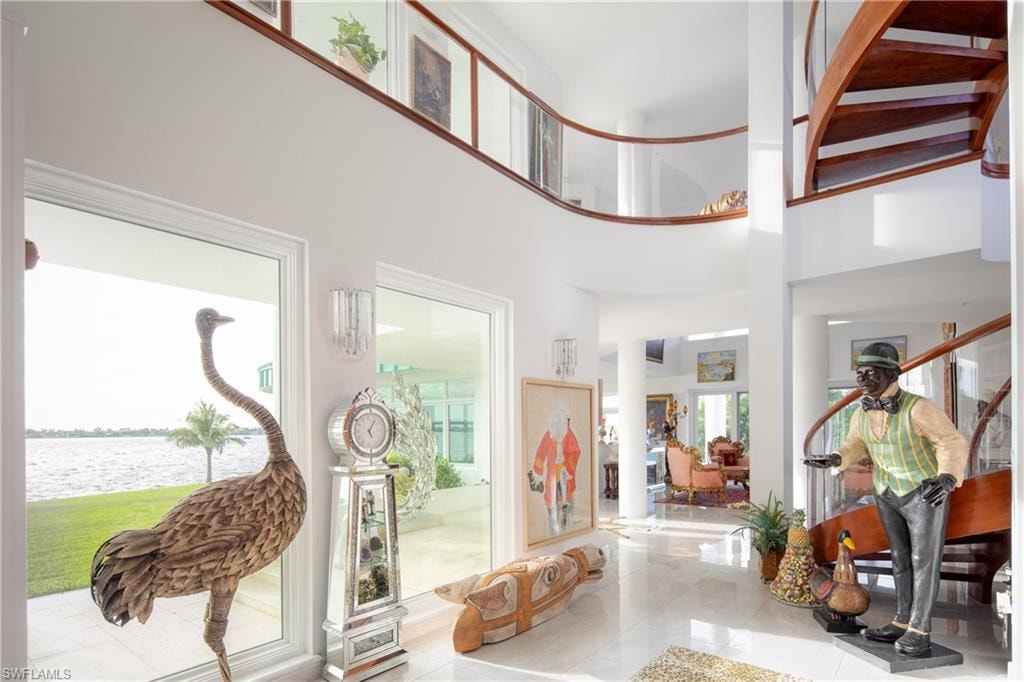 Tiled entrance foyer with a high ceiling, a water view, and stairs