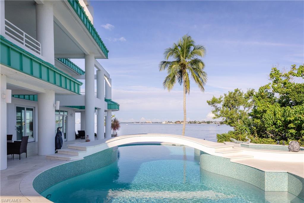 Swimming pool with a patio, a water view, and a balcony