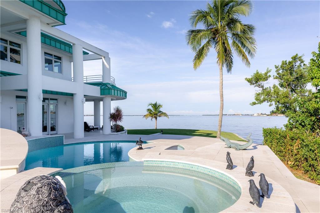 View of pool featuring a water view, a patio, french doors, and a pool with connected hot tub
