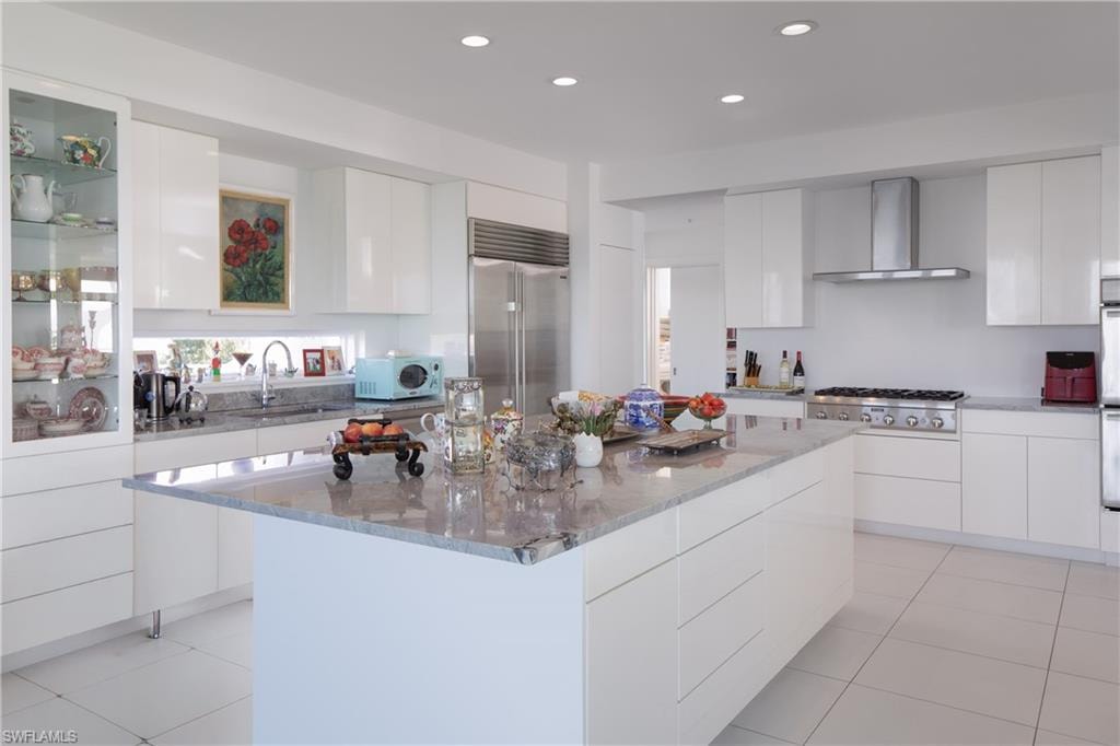Kitchen with modern cabinets, white cabinets, light stone counters, and recessed lighting