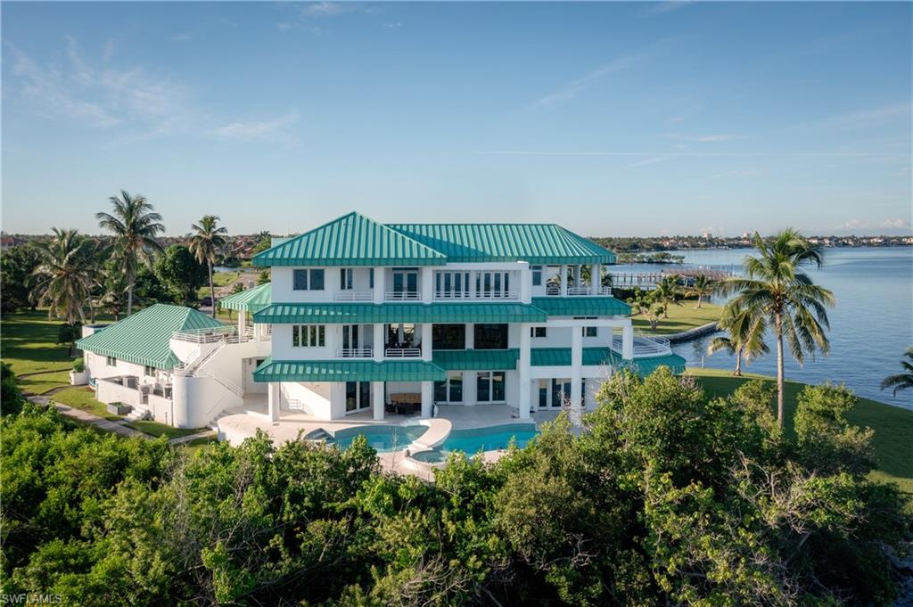 Back of property with a balcony, a patio, stairway, a metal roof, and a standing seam roof