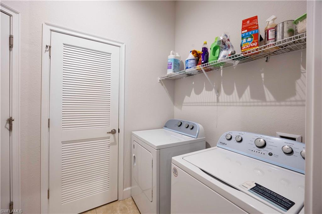 Washroom with washer and dryer and light tile patterned floors