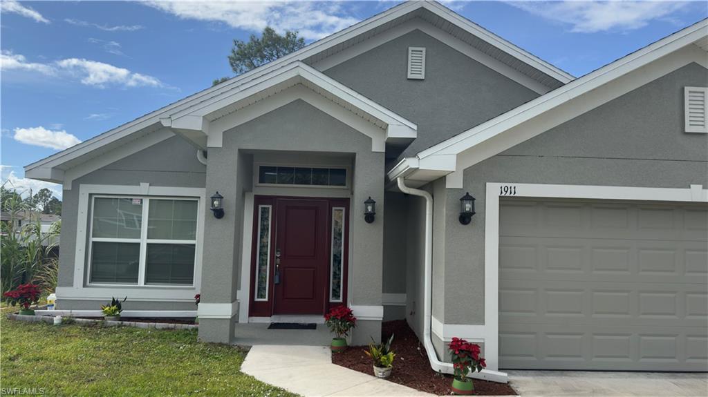 View of front of property featuring stucco siding, an attached garage, and a front yard