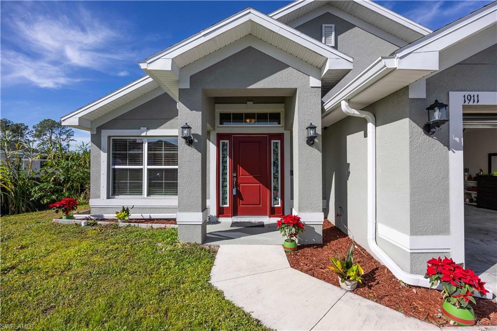 View of exterior entry with stucco siding and a yard