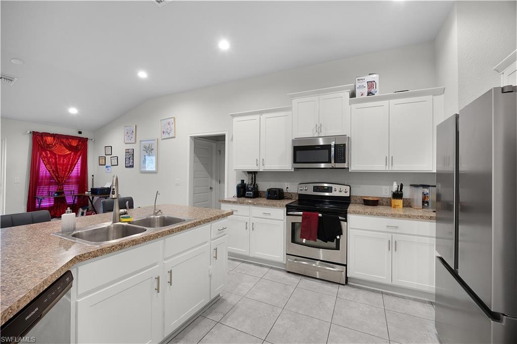 Kitchen featuring appliances with stainless steel finishes, white cabinets, recessed lighting, light countertops, and vaulted ceiling