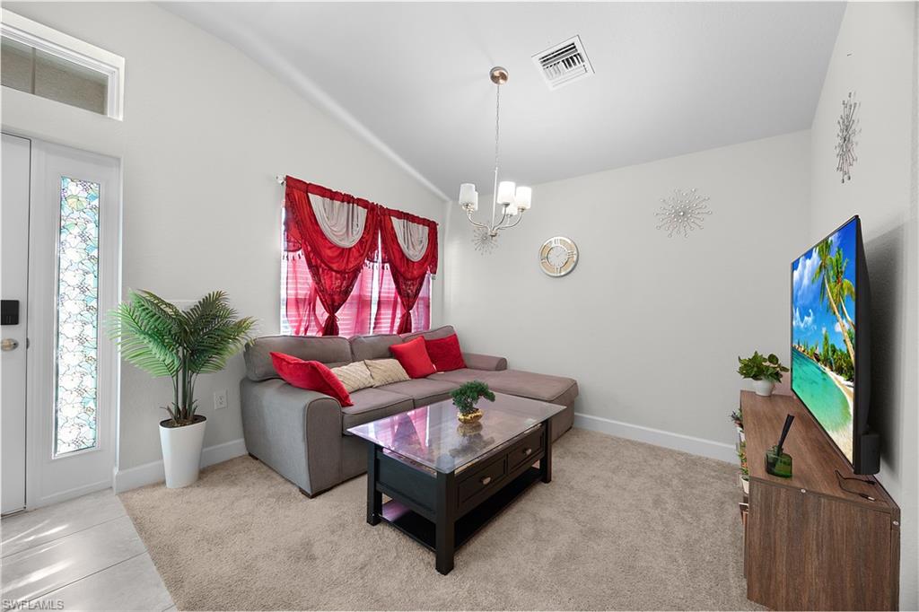 Carpeted living room featuring a chandelier and vaulted ceiling