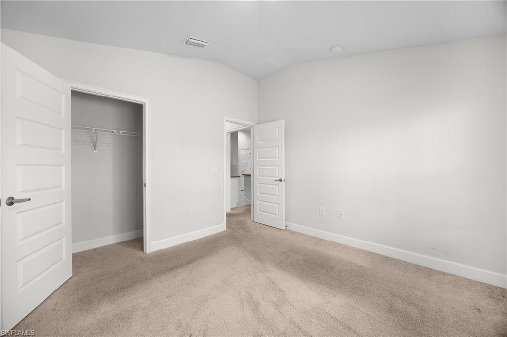 Unfurnished bedroom featuring carpet flooring, lofted ceiling, and a closet