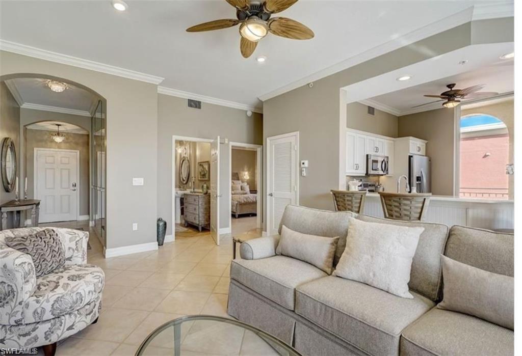 Living area featuring crown molding, a ceiling fan, arched walkways, light tile patterned flooring, and recessed lighting