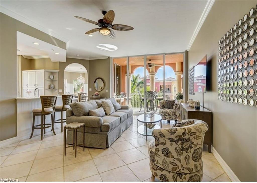 Living room with crown molding, a wall of windows, ceiling fan, light tile patterned floors, and arched walkways