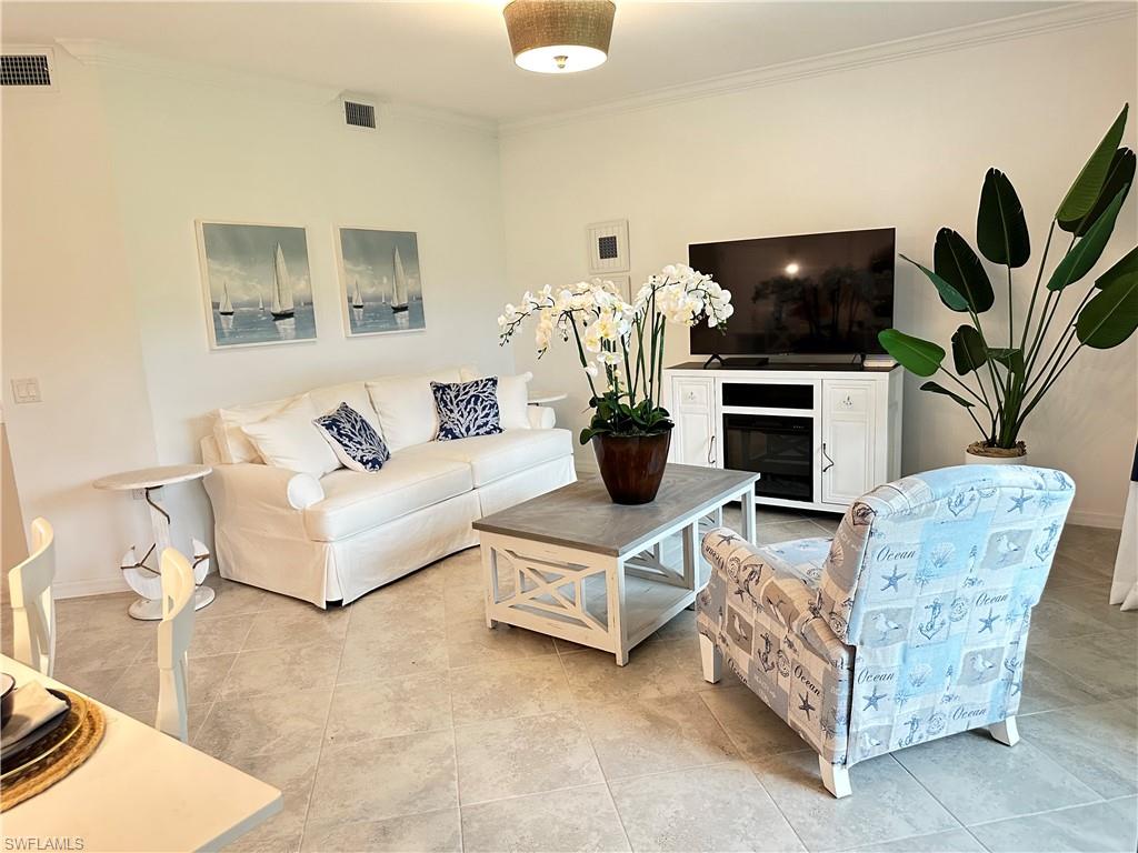 Living room featuring light tile patterned flooring and crown molding