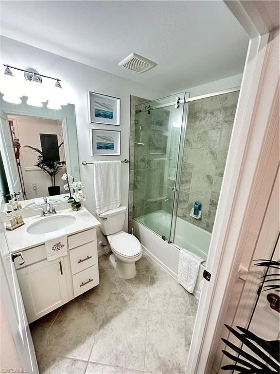 Full bathroom featuring vanity, combined bath / shower with glass door, toilet, and tile patterned floors