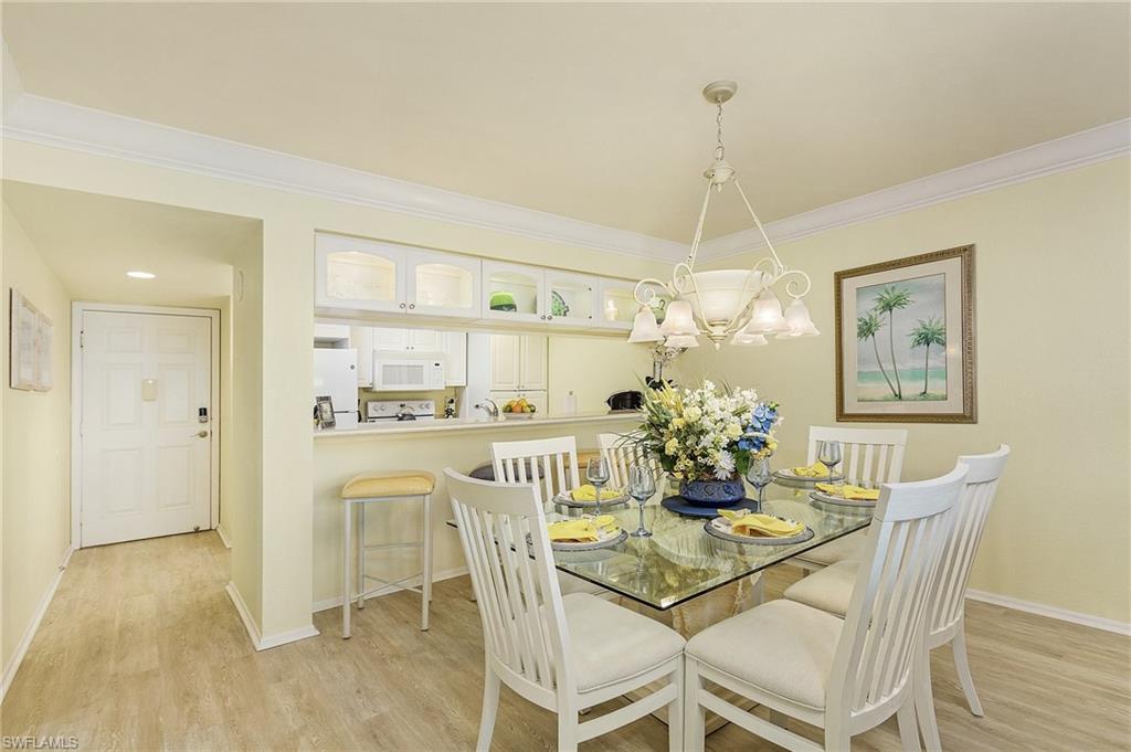 Dining space with light hardwood / wood-style floors, crown molding, and a chandelier