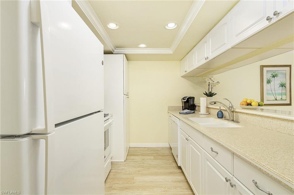Kitchen featuring crown molding, sink, light wood-type flooring, white cabinets, and white appliances