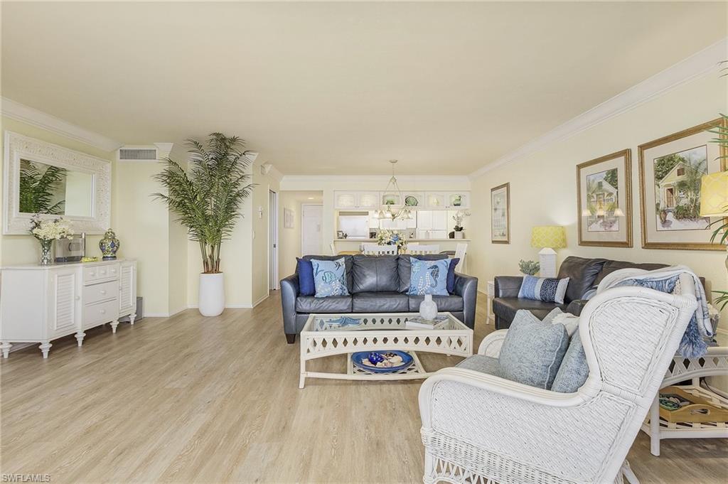Living room featuring light hardwood / wood-style floors, crown molding, and an inviting chandelier