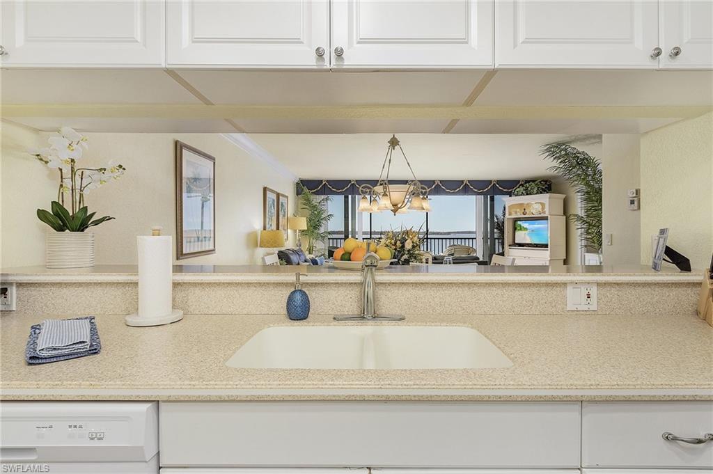 Kitchen featuring dishwasher, sink, a notable chandelier, decorative light fixtures, and white cabinetry