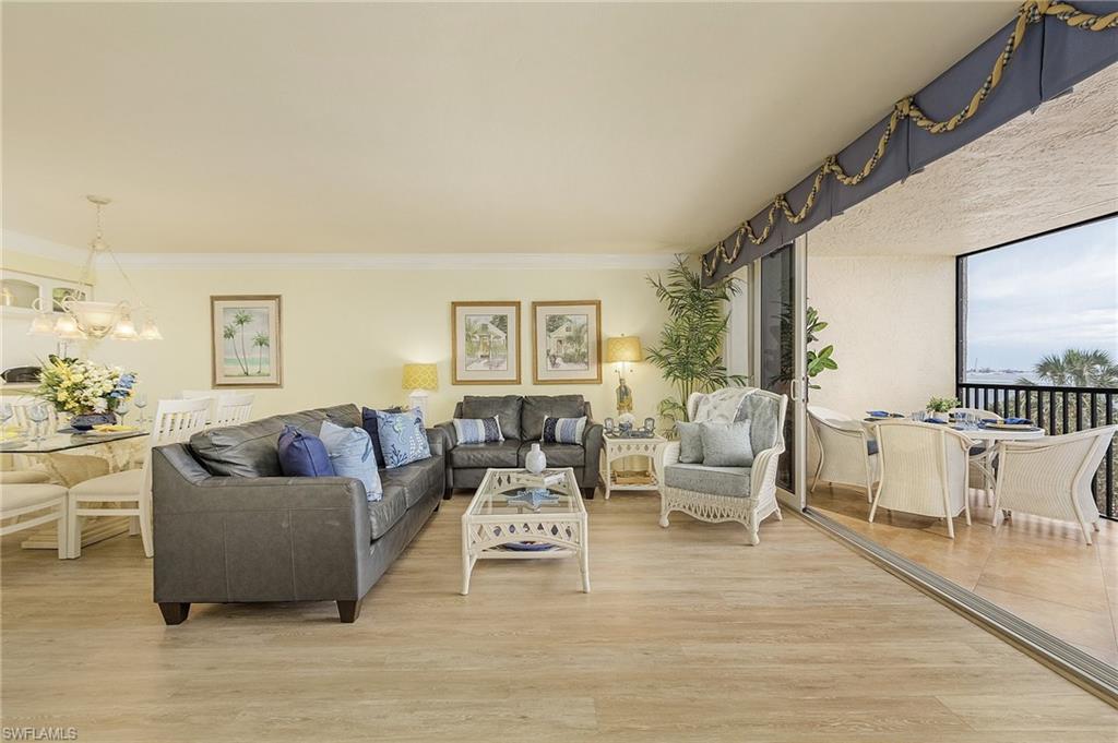 Living room with light hardwood / wood-style floors, crown molding, and a chandelier