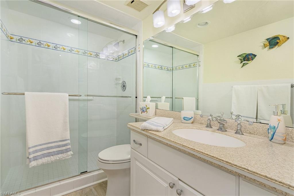 Bathroom featuring toilet, an enclosed shower, vanity, and wood-type flooring