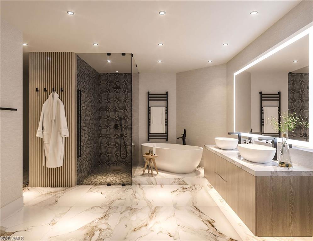 Bathroom featuring double vanity, a soaking tub, a towel warmer, a walk in shower, and recessed lighting