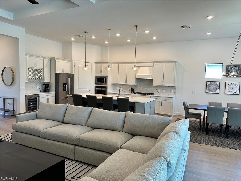 Living area featuring wine cooler, light wood finished floors, and recessed lighting