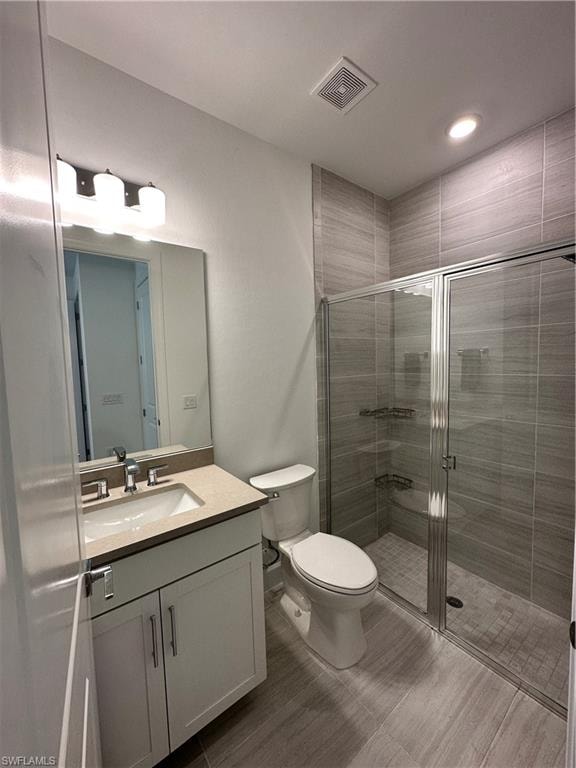 Bathroom with a stall shower, vanity, and recessed lighting