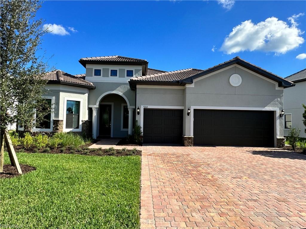 Mediterranean / spanish home with stucco siding, stone siding, and a front lawn