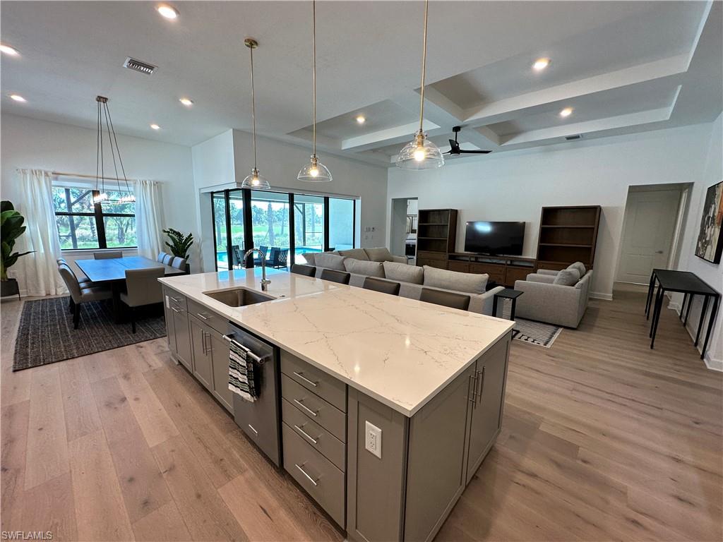 Kitchen with gray cabinetry, pendant lighting, light wood finished floors, coffered ceiling, and beamed ceiling