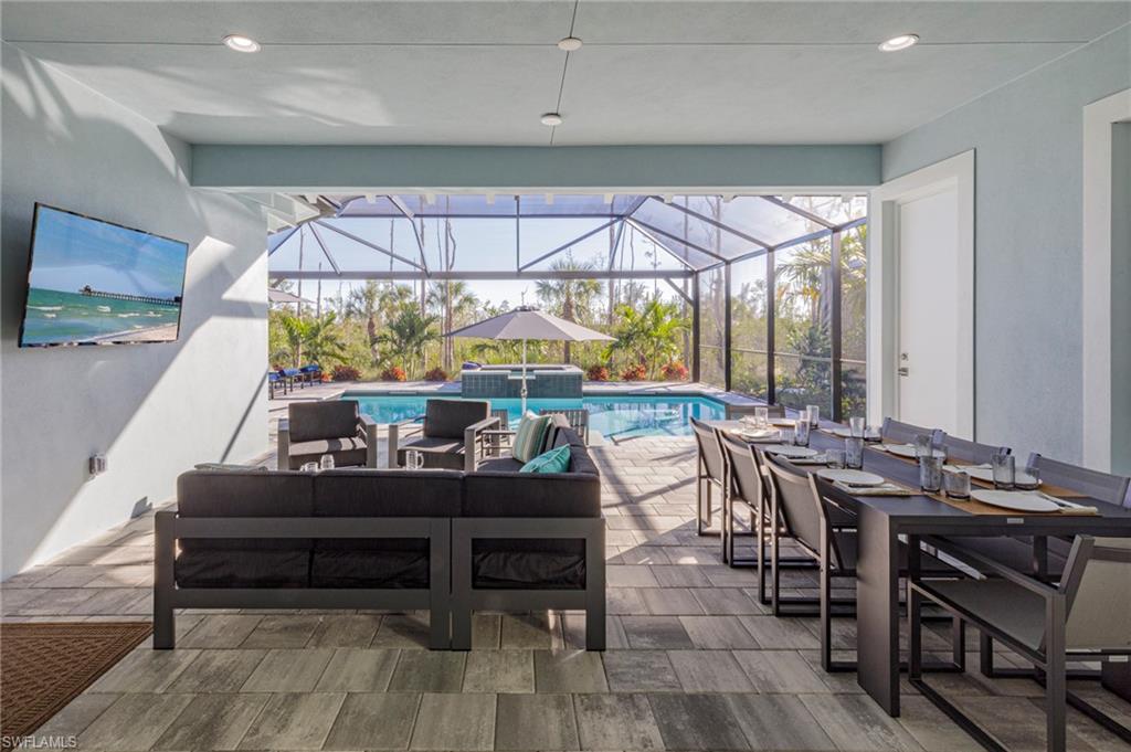 View of pool featuring glass enclosure, an outdoor living space, and a patio